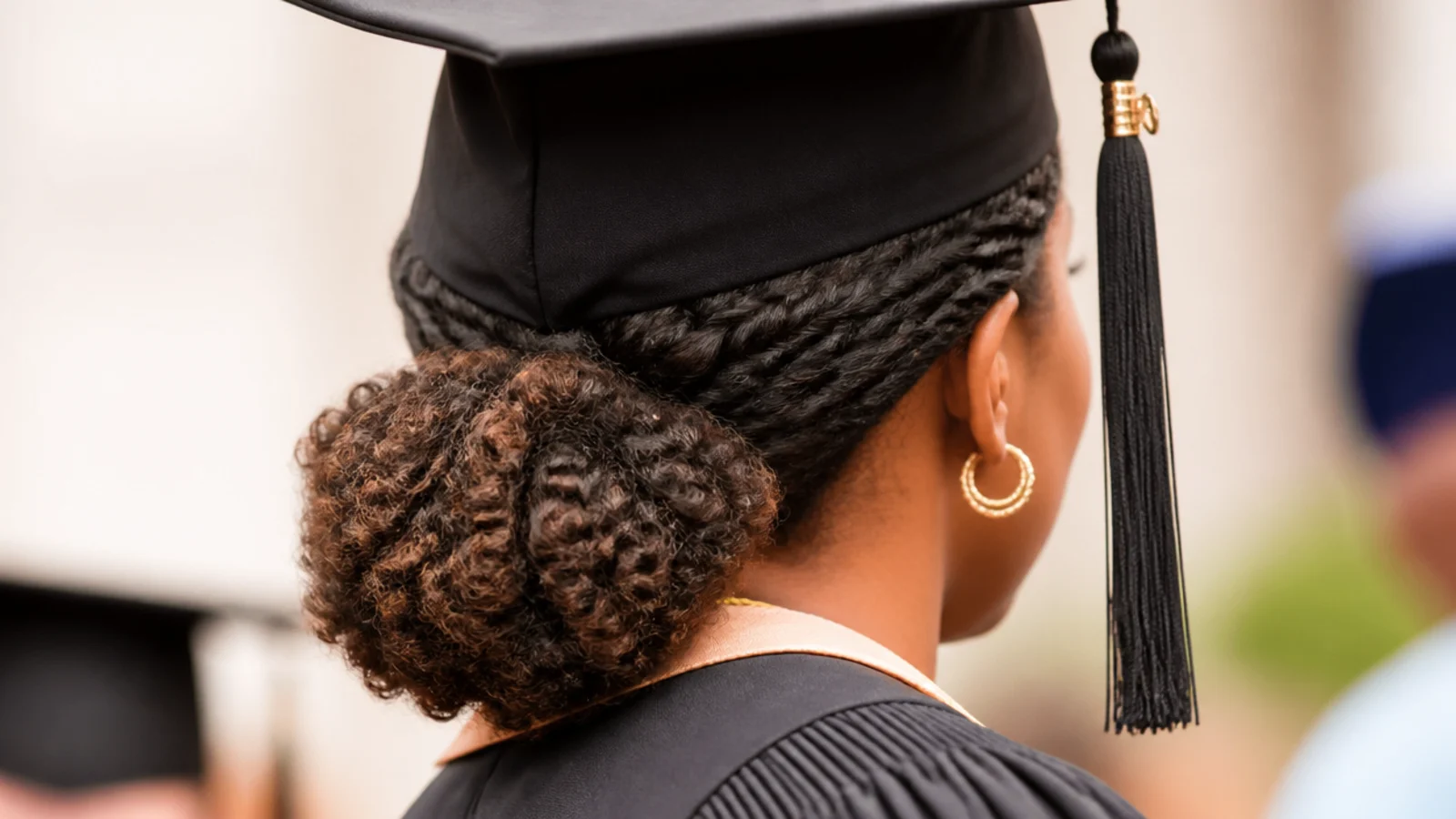 Flat twisted sides gathered into a low puff at the nape, a natural hair graduation style under a cap