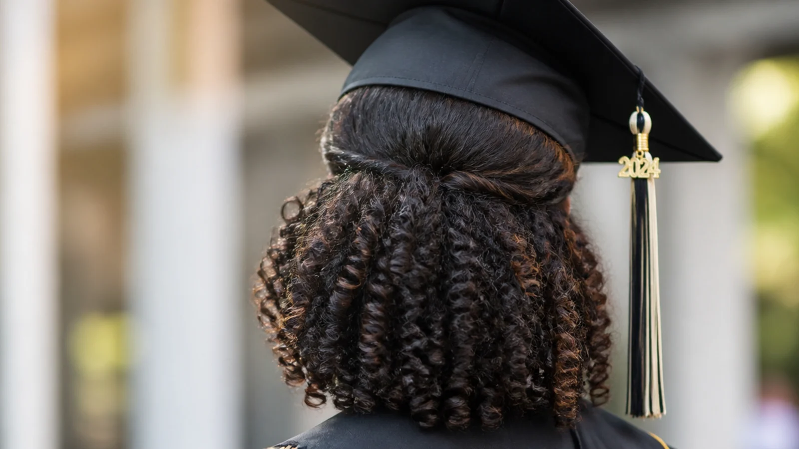 Half-up curly puff with the graduation cap positioned behind the gathered section