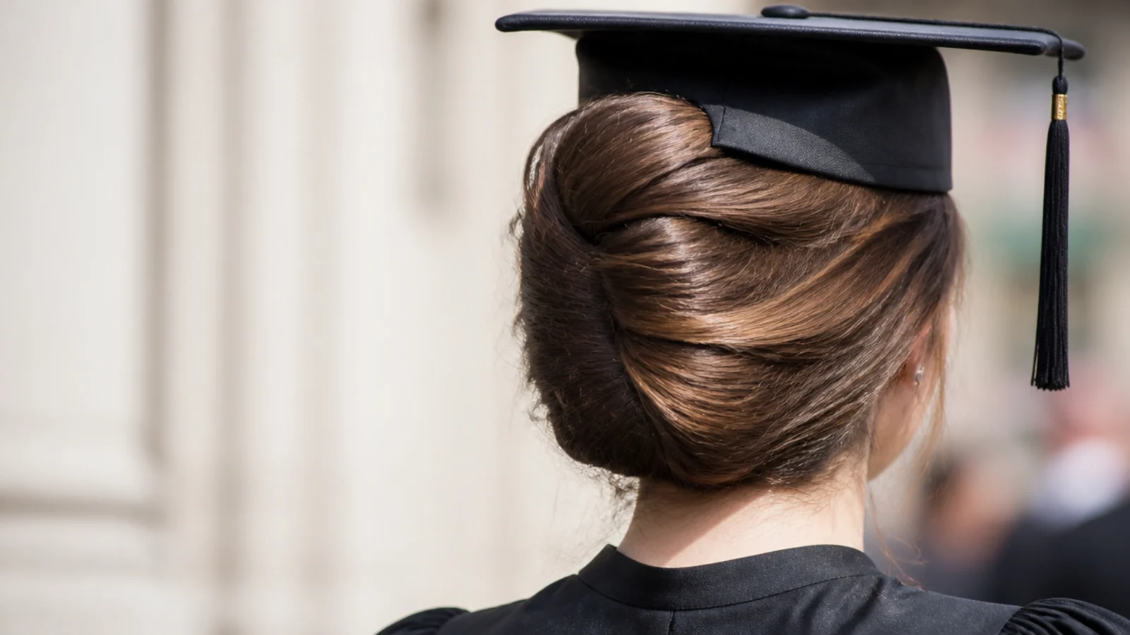 Long thick hair in a vertical French twist pinned flat at the back of the head below the cap band