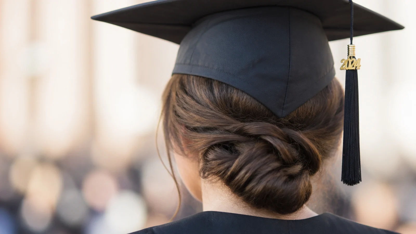 Low chignon graduation hairstyle coiled at the nape of the neck under a black mortarboard cap