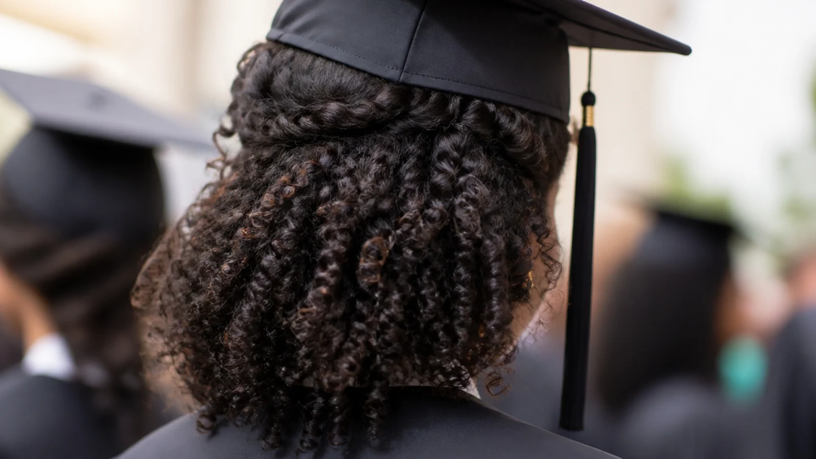 Curly wash and go graduation hairstyle with cap and curls pinned back at both temples