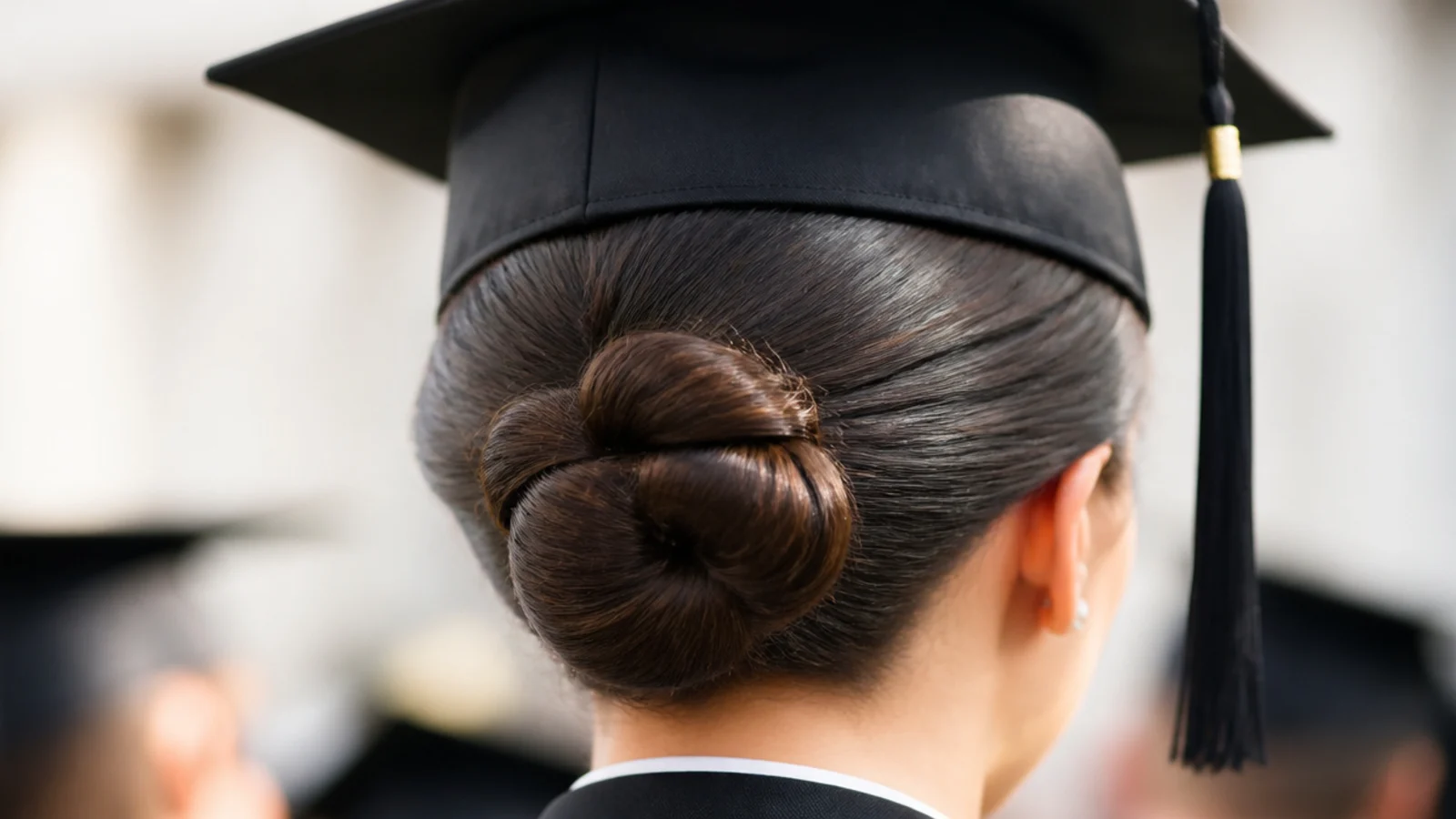 Wet look slicked back bun graduation hairstyle with high shine at the crown and a small coiled bun