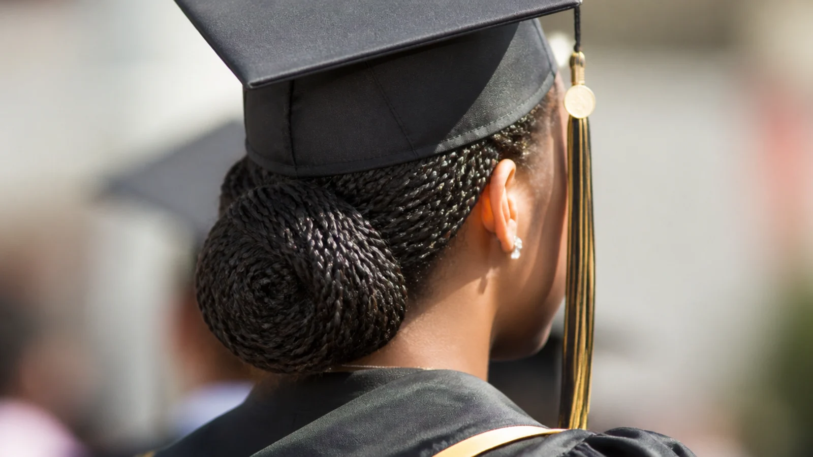 Sleek low bun graduation hairstyle gathered from knotless braids and coiled at the nape