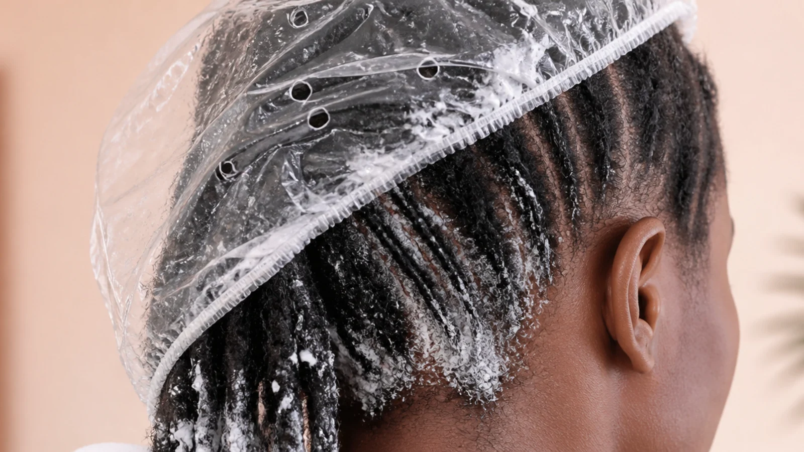 Plastic processing cap over sectioned 4C hair coated in thick white deep conditioner