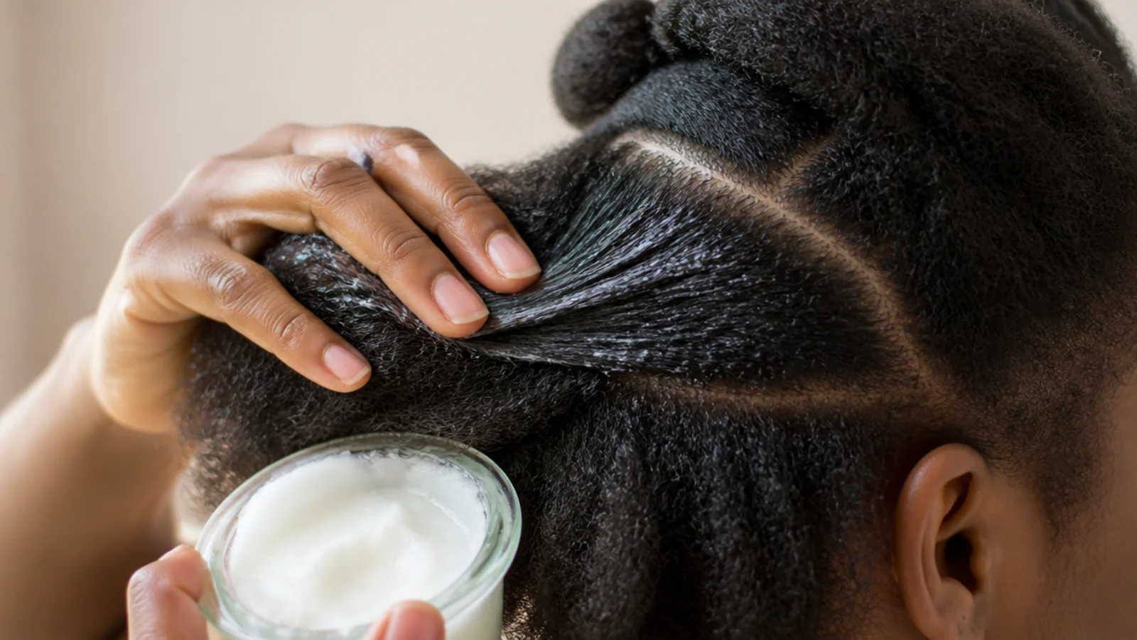 Coconut oil being smoothed through dry sectioned 4C hair as a pre-shampoo treatment