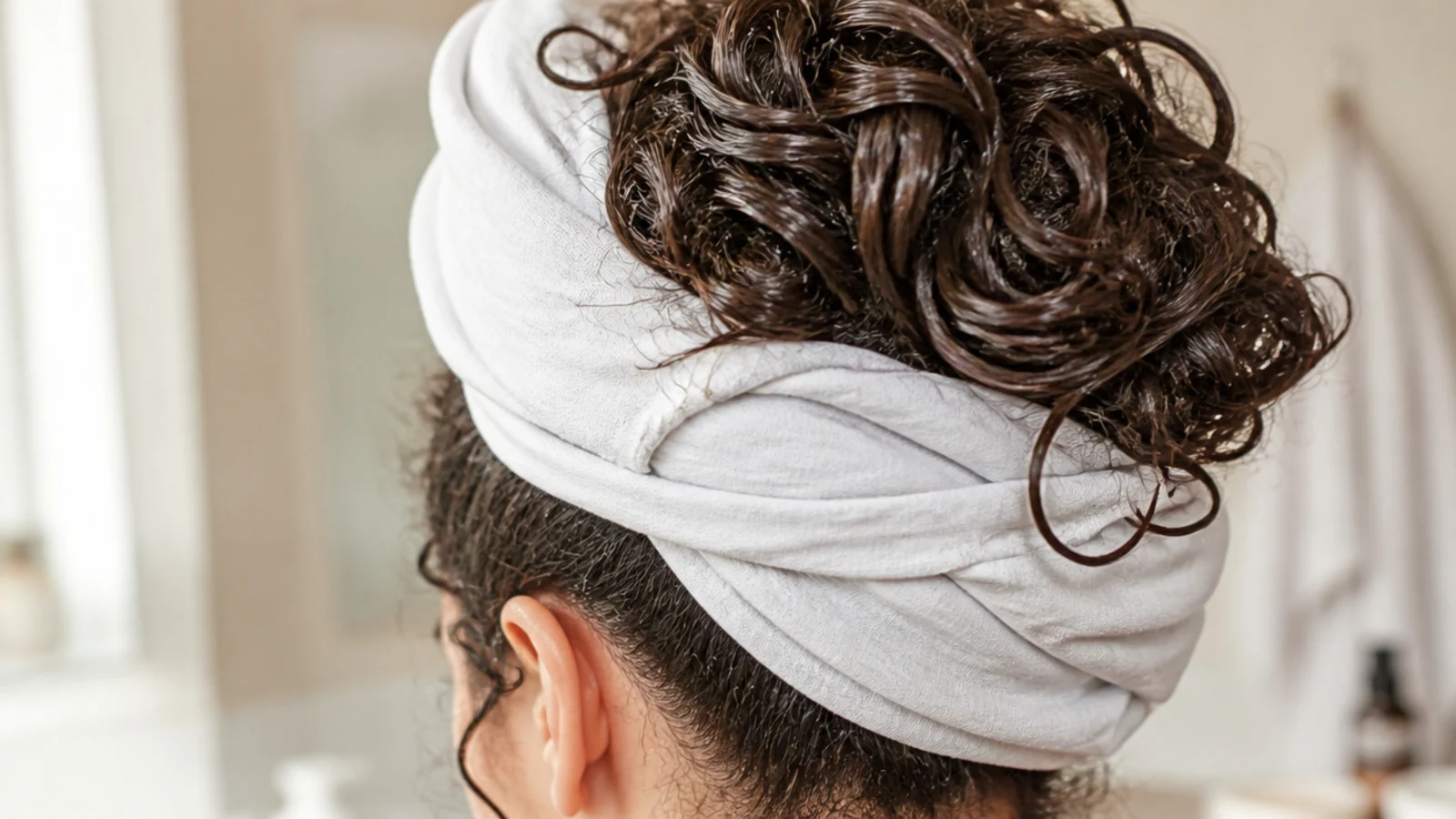 Curly hair wrapped and plopped in a cotton t-shirt on top of the head after washing