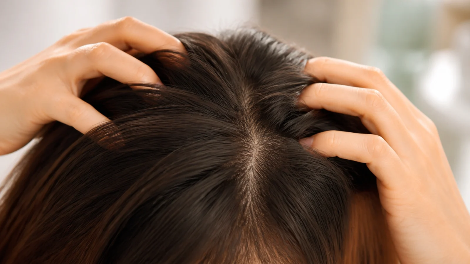 Fingertips massaging the crown of the scalp in small circles for hair growth