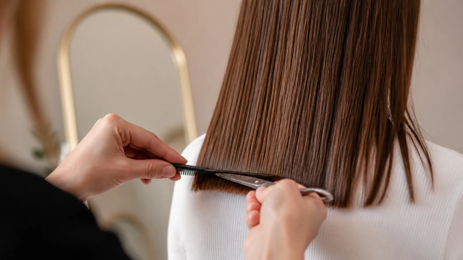 Hairdresser trimming a quarter inch off blunt ends of long hair to prevent split ends