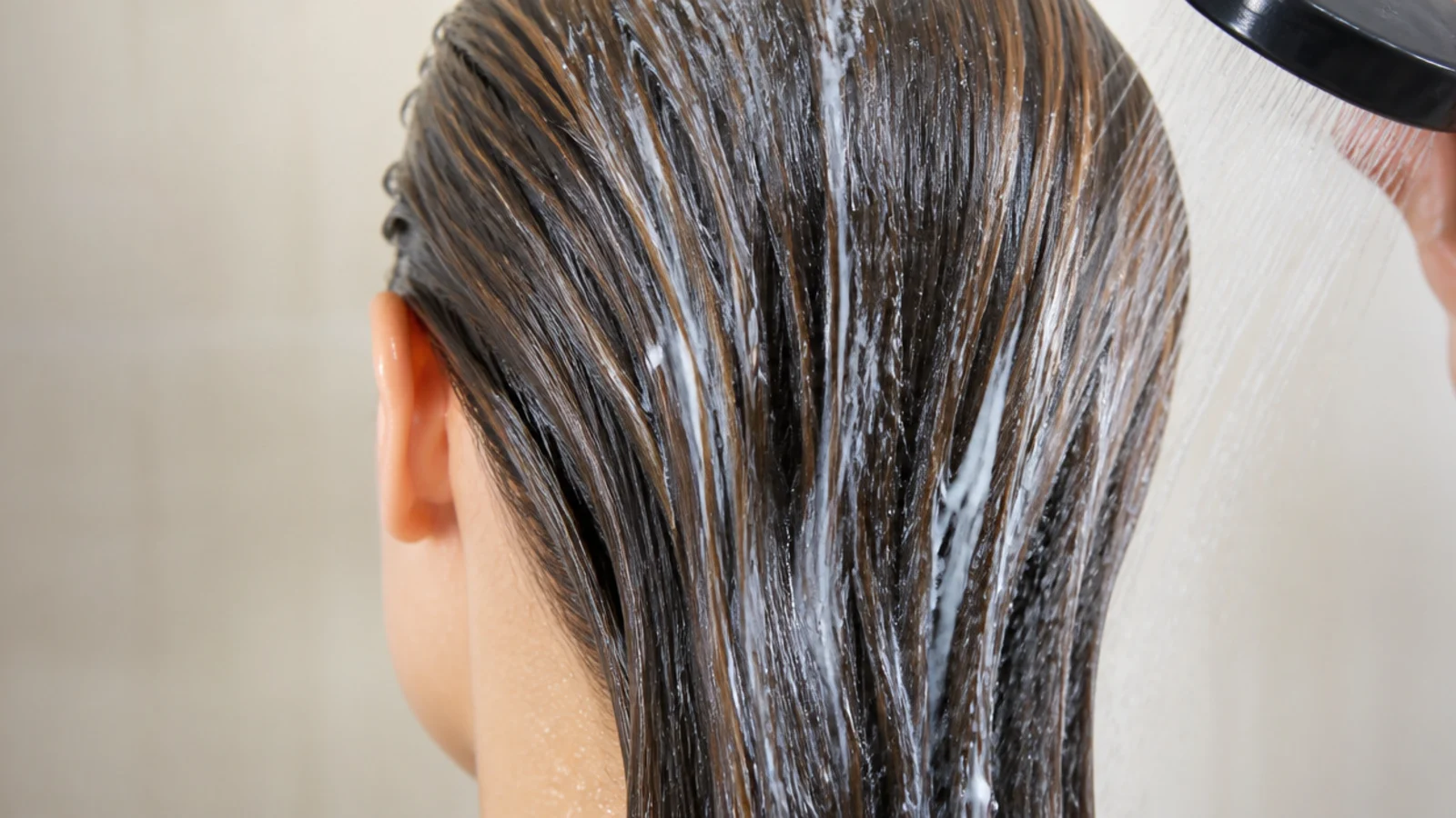 Hair being rinsed with fresh water and coated in conditioner before entering a chlorinated pool