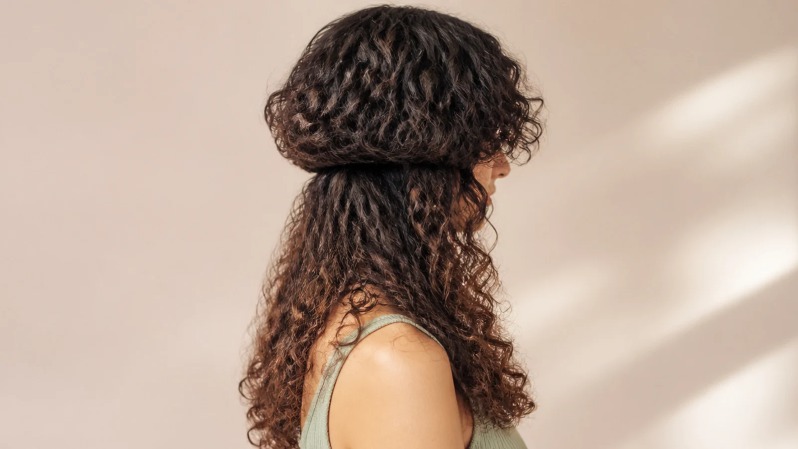 Curly jellyfish haircut with middle-parted curtain bangs framing the face above long curly lengths