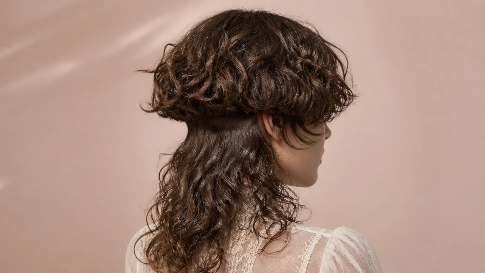 Curly jellyfish haircut with a hidden nape undercut revealed under long curly lengths