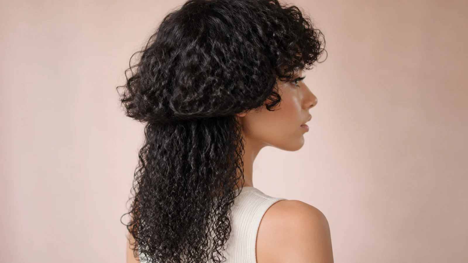 Curly jellyfish haircut with short cropped curly bangs sitting above the eyebrows over defined coils