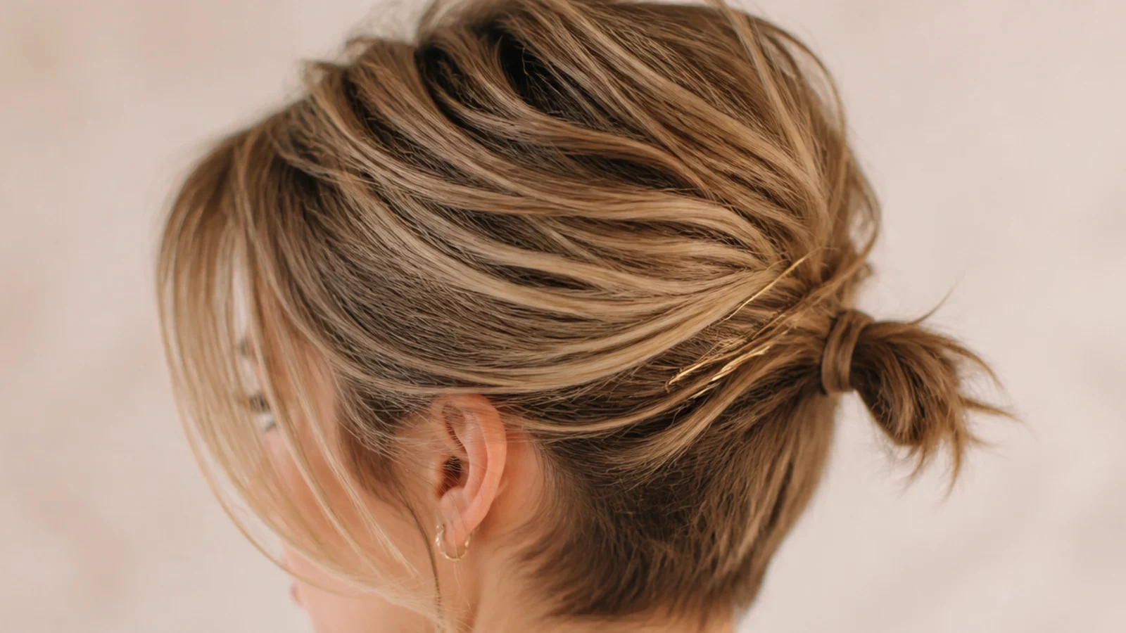 Tiny nape ponytail on a grown-out pixie with the sides pinned back and soft crown volume