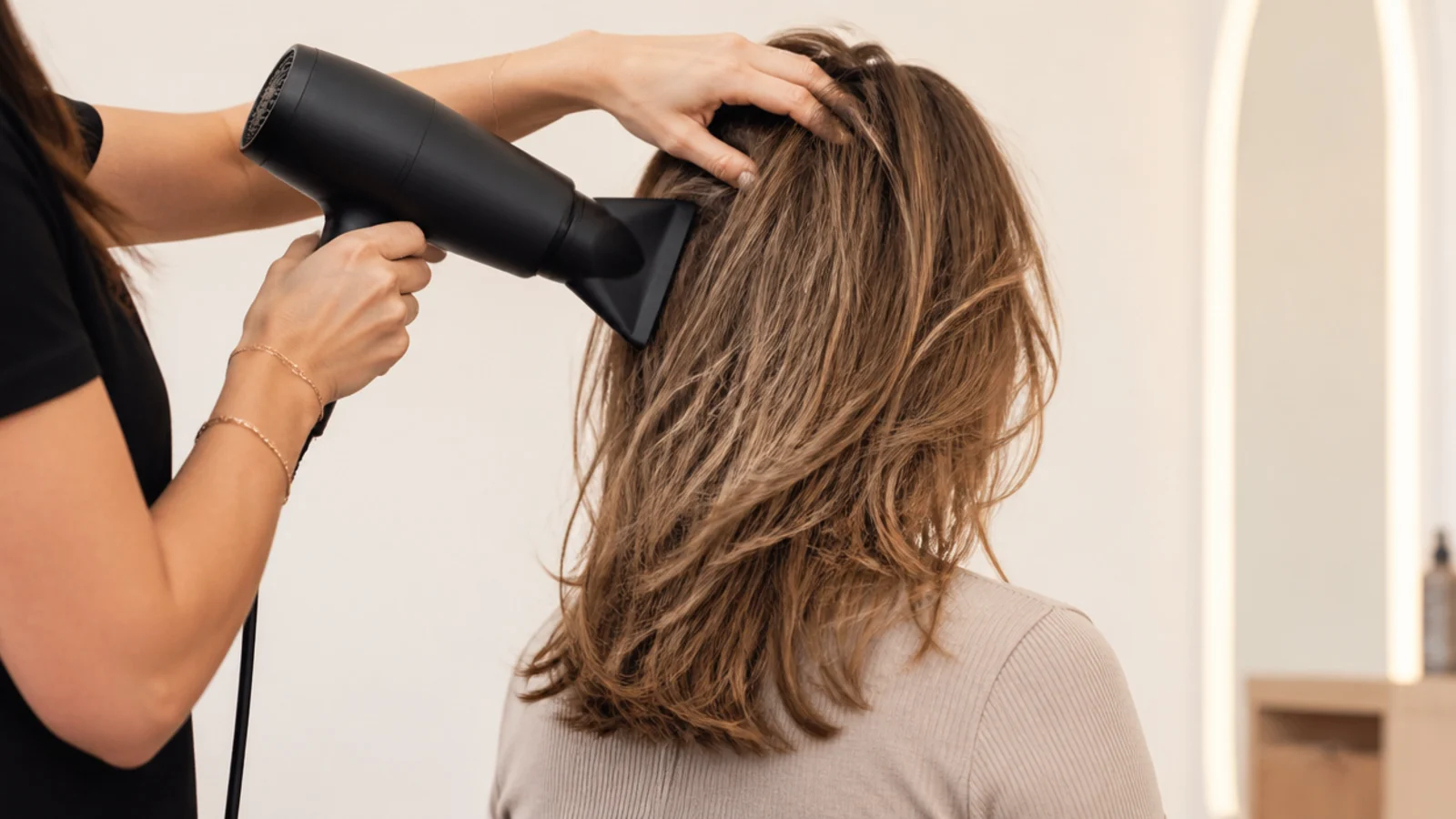 Blow dryer rough-drying mid length hair with fingers at the roots before brush styling