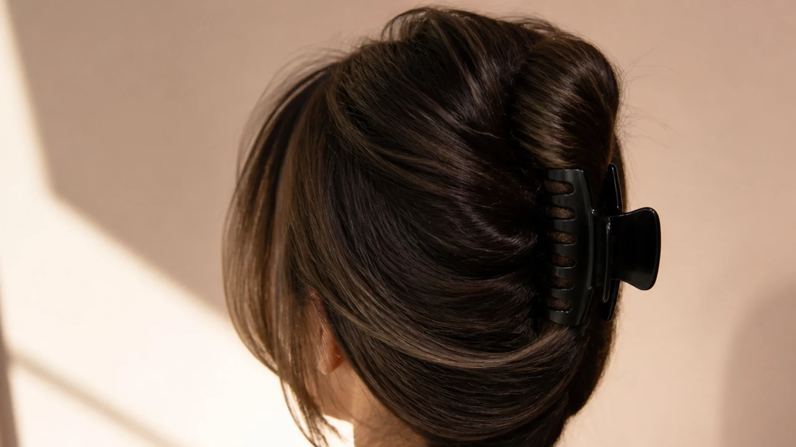 Black hair twisted into a French twist and secured with a large black claw clip, shot from behind