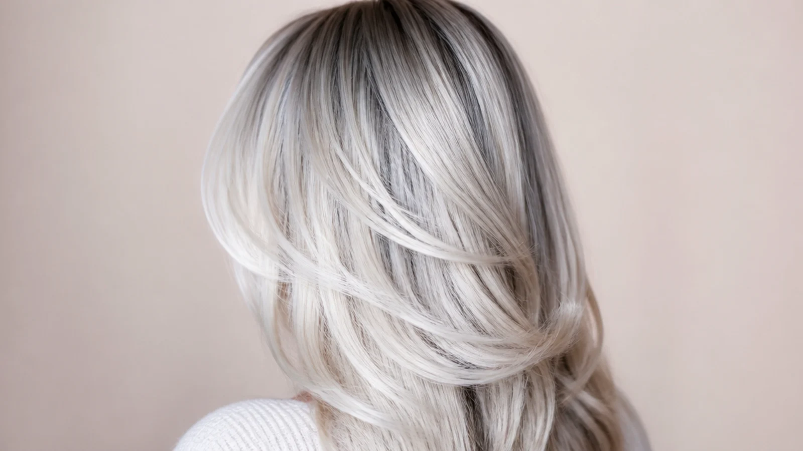 Cool blue silver ash blonde long hair with a soft shadow root and rounded layers, back view