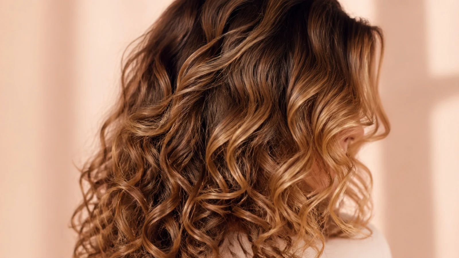 Bronde brown curly hair with defined 2b to 3a spirals and shorter curtain pieces at the front