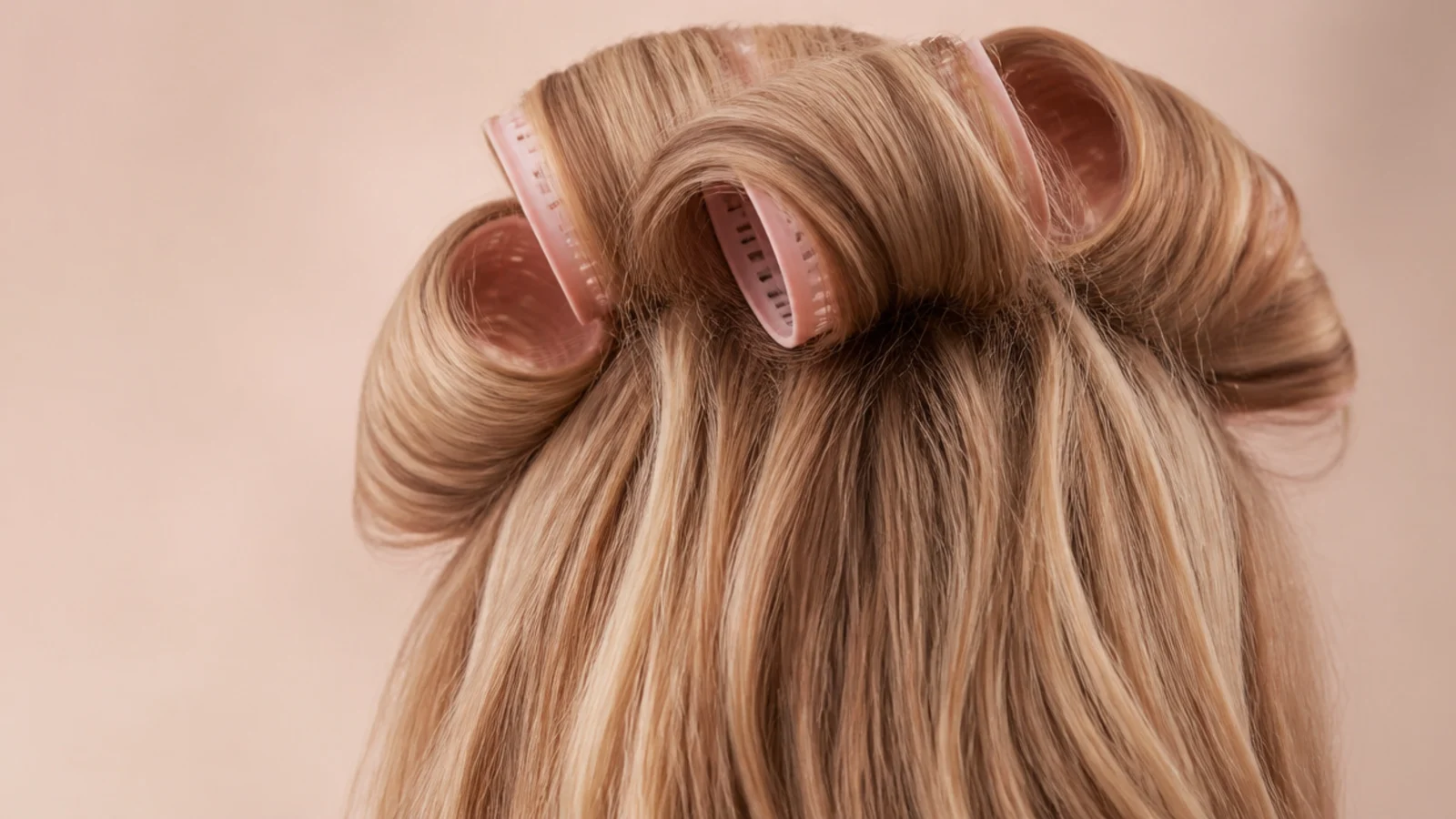 Blonde hair set in large hot rollers at the crown for volume, photographed from behind