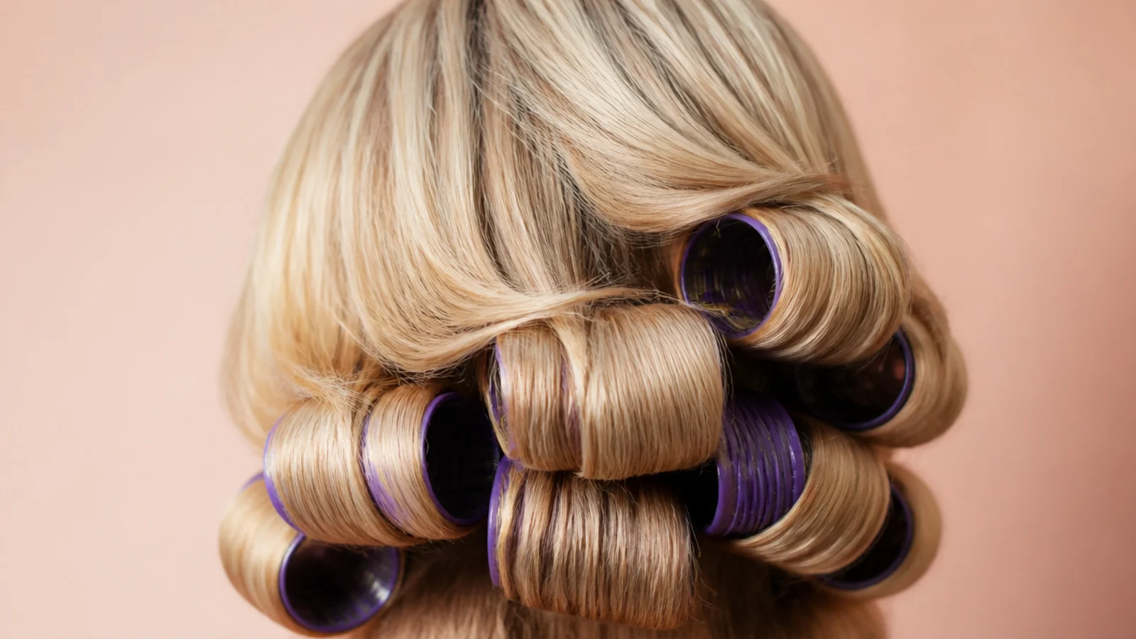 Blonde hair set on large purple flexi rods for uniform stretched curls, back view