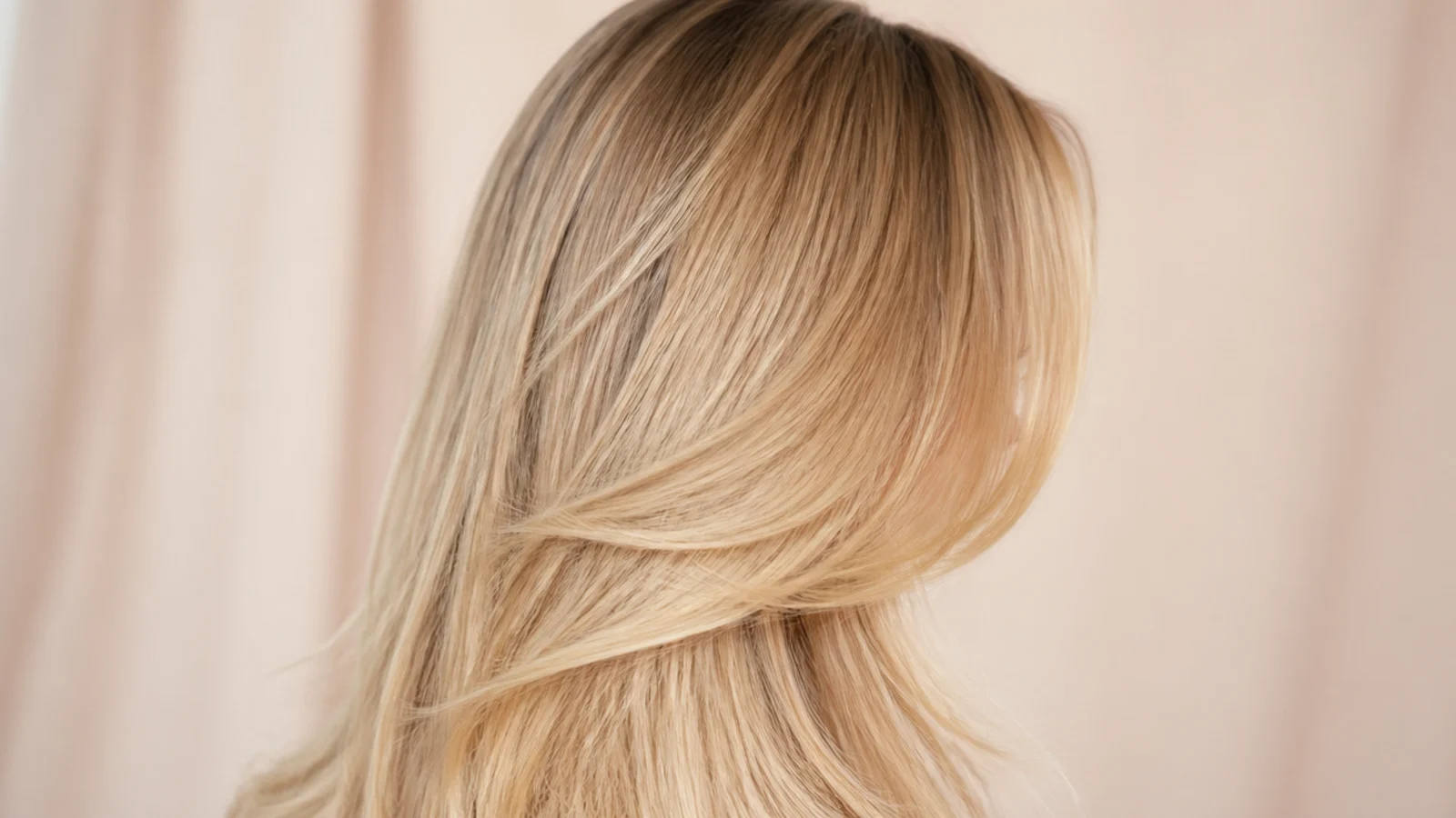 Buttery blonde long hair with a soft darker shadow root melting into golden lengths, back view