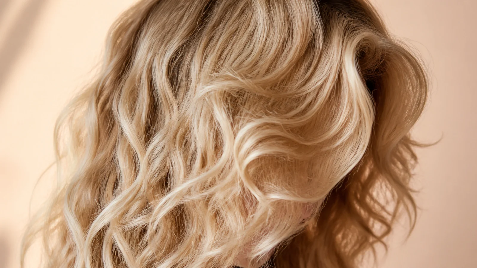 Curtain bangs cut into naturally curly 2c blonde hair with defined S waves around the face