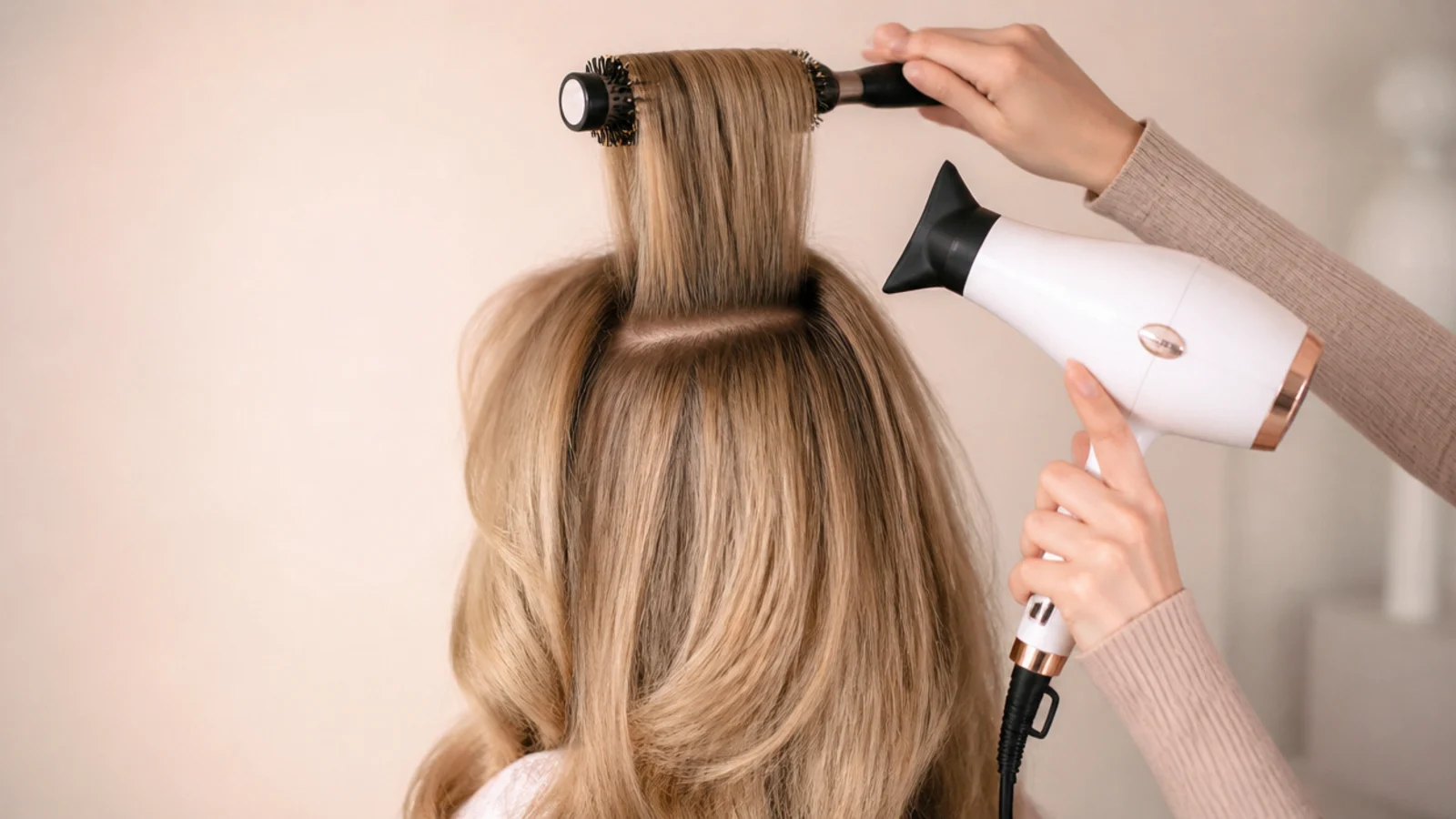 Crown section of blonde hair pulled straight up on a round brush to build root volume