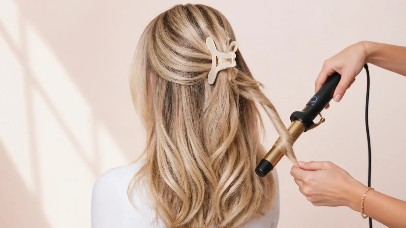 A 1 inch curling iron adding a soft bend to the mid-lengths of long layered blonde hair