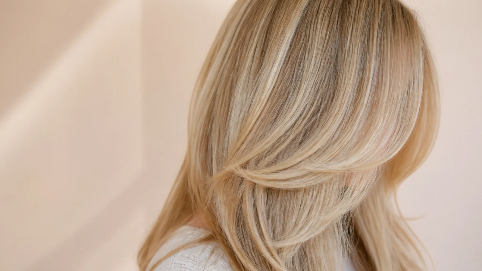 Long blonde hair with face-framing layers beginning at the jawline and blending into the lengths
