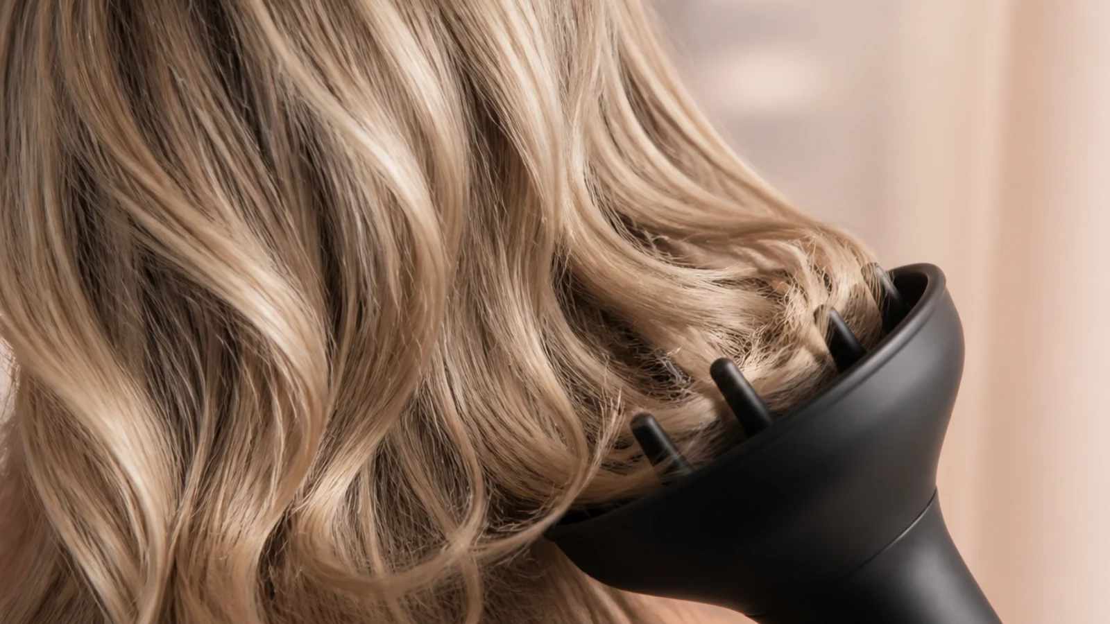 Diffuser attachment cupping blonde waves at the ends to dry natural texture with volume