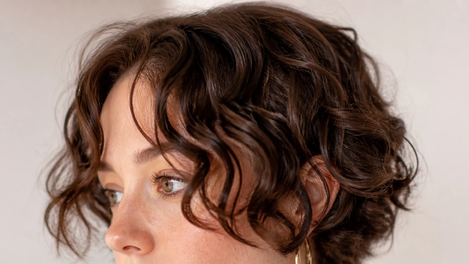 Curly short curtain bangs on a round face with the shortest point kept at cheekbone level