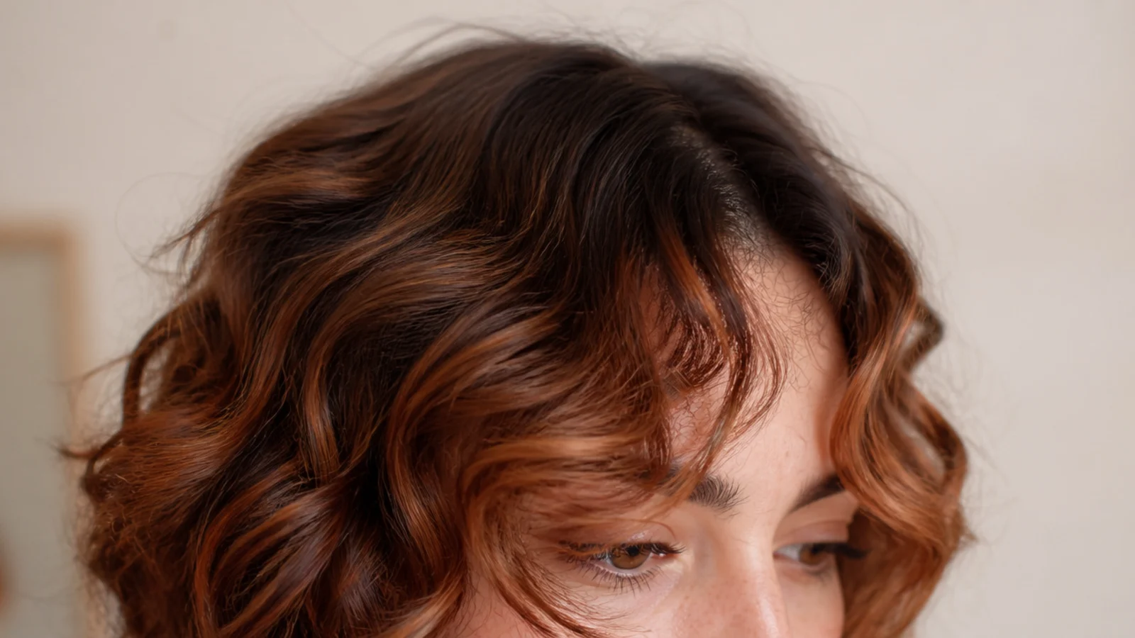 Curly short curtain bangs lit with copper balayage through the face-framing pieces