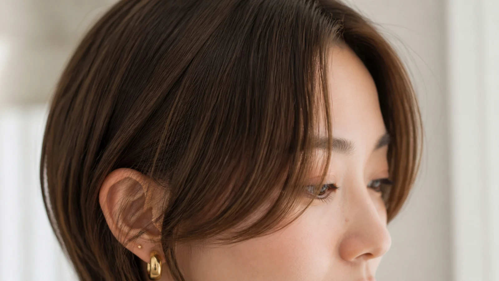 Grown out short curtain bangs on a round face with the shortest point sitting below the cheekbone