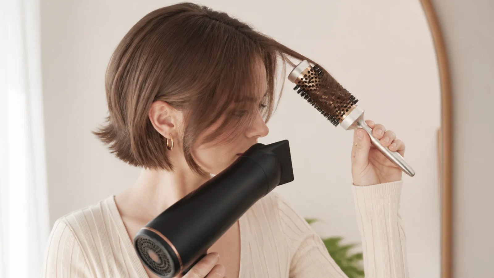 Blow-drying short curtain bangs on fine hair with a 1 inch round brush sweeping away from the center part