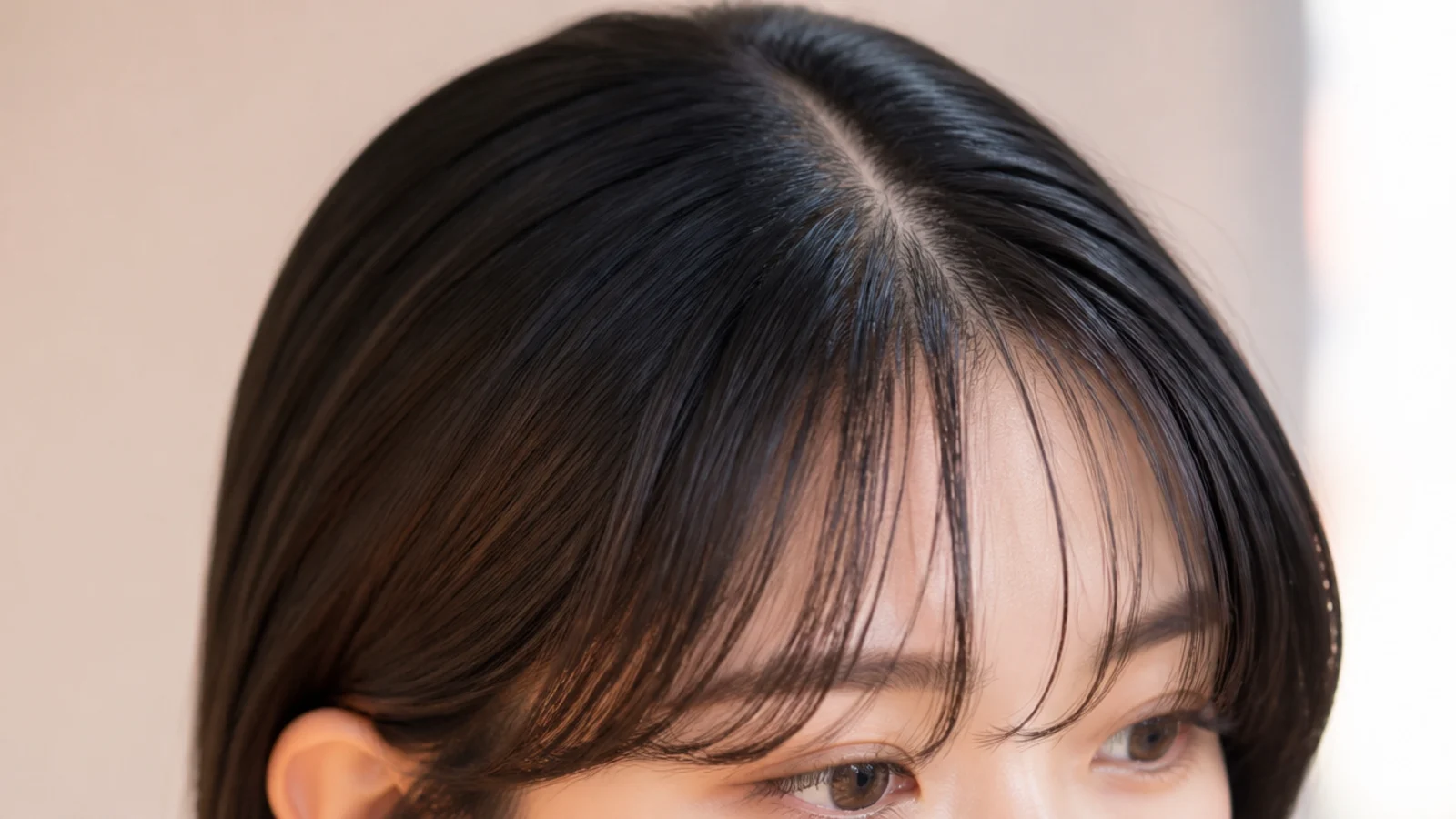 Wispy short curtain bangs on sleek straight dark hair with a clean center part