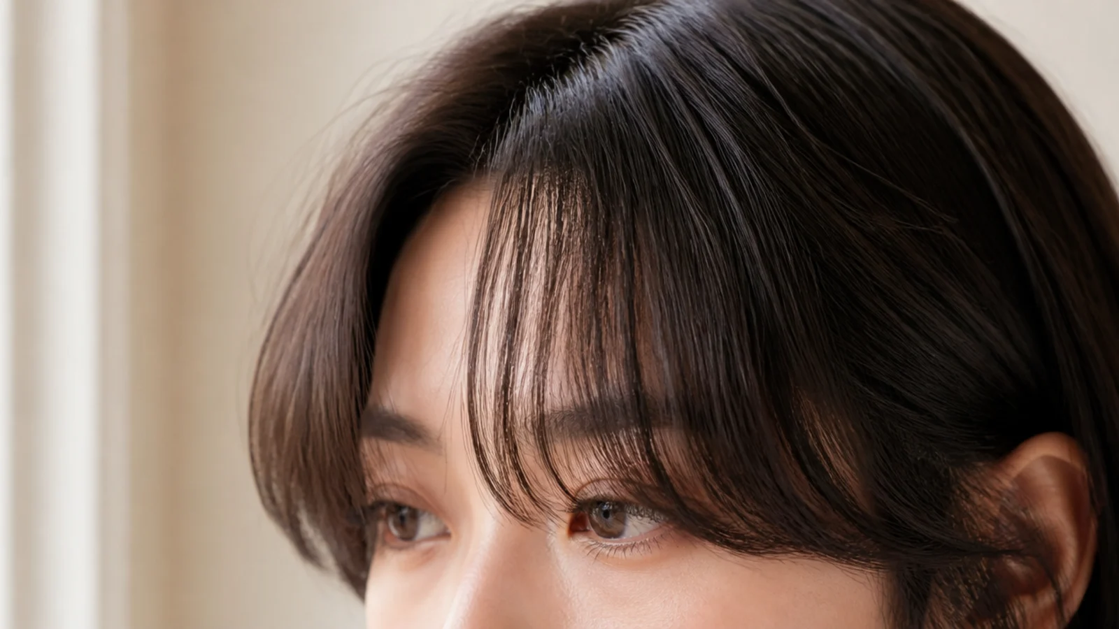 Wispy short curtain bangs on thick dark hair with weight removed from behind the fringe