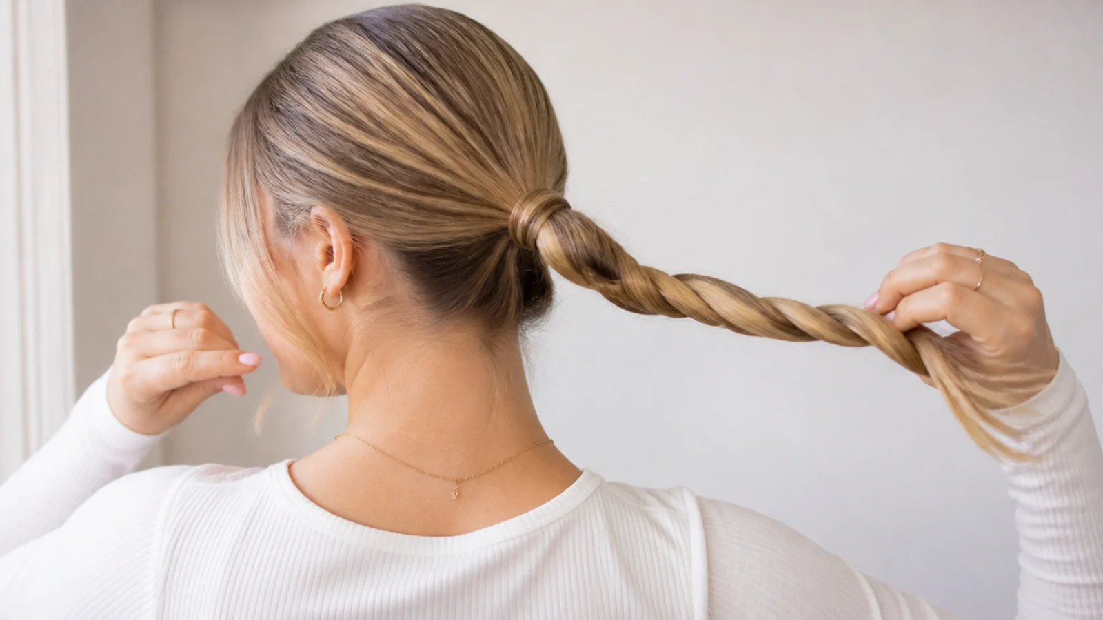 Faceless close-up of a ponytail being twisted into a tight rope for a no-heat low bun