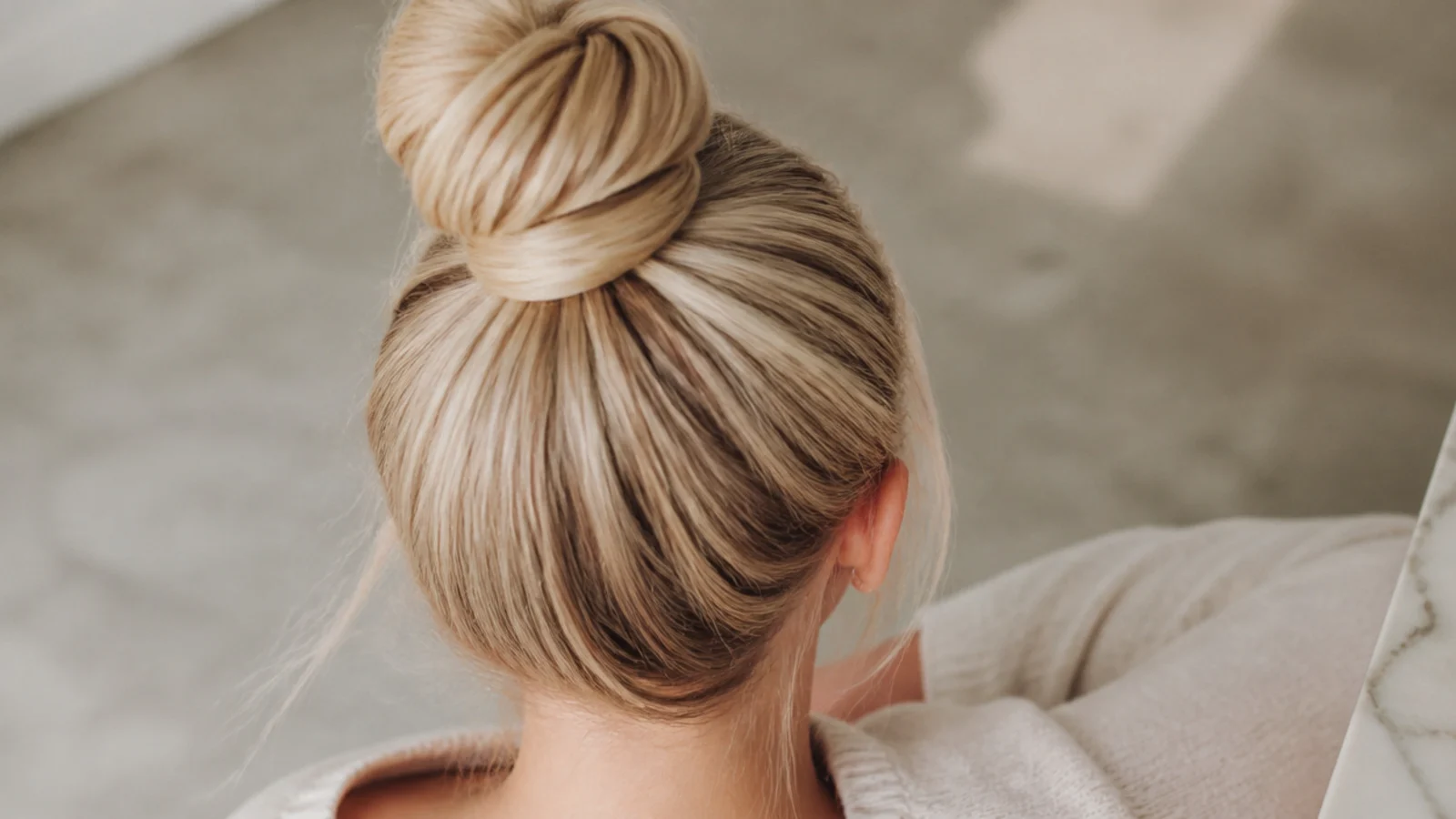 Faceless top-back view of a high top knot anchored with a wrapped elastic on fine hair