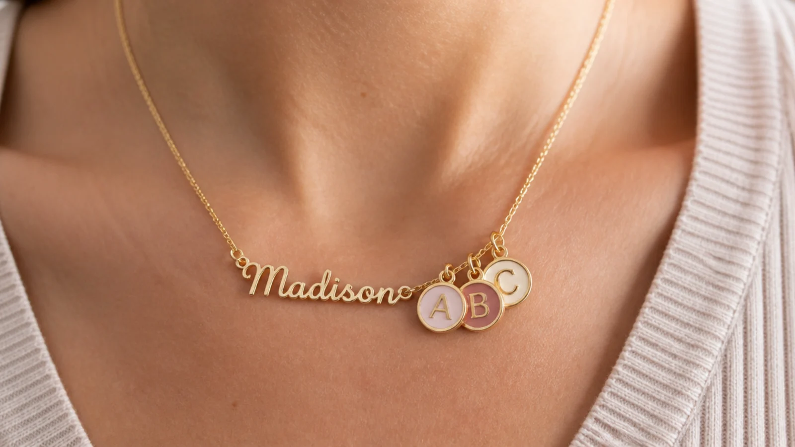 Faceless close-up of a personalized nameplate necklace and colorful initial pendants