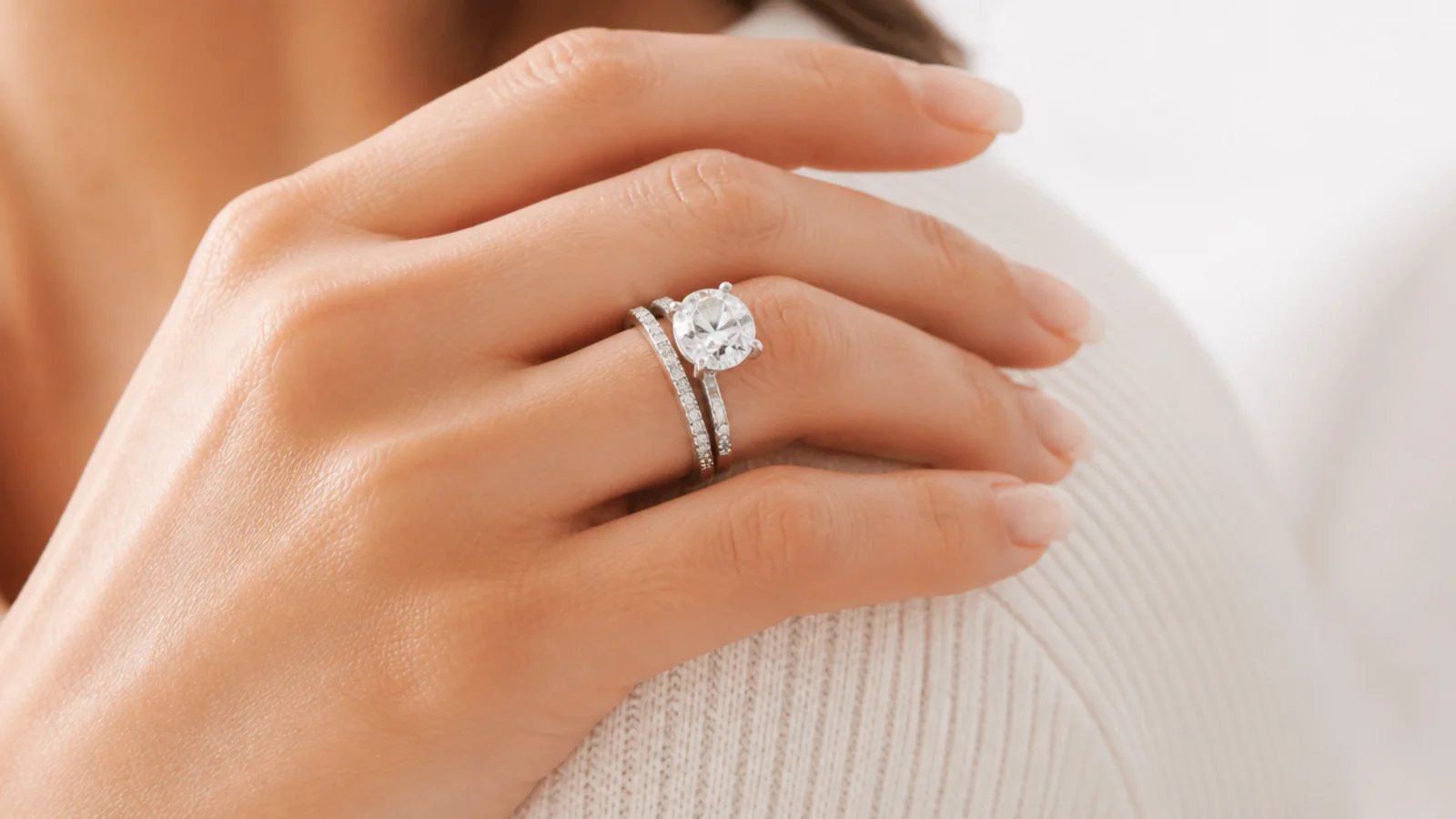 Faceless close-up of a lab-grown diamond engagement ring and a thin pave wedding band in white gold