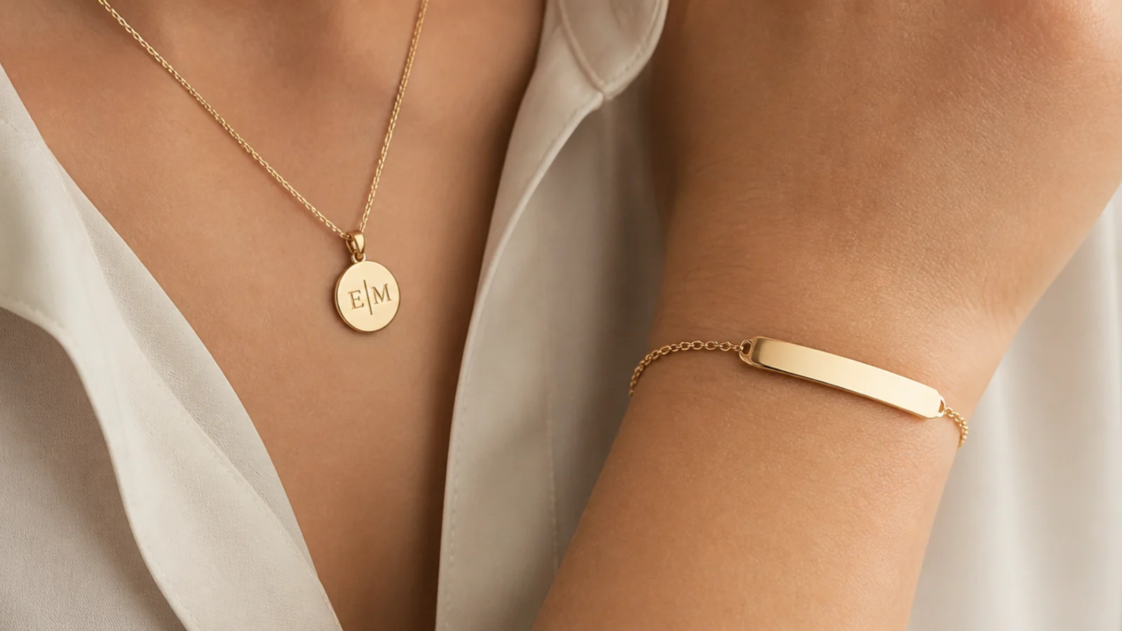 Faceless close-up of an engravable gold pendant and friendship chain bracelet with a smooth bar