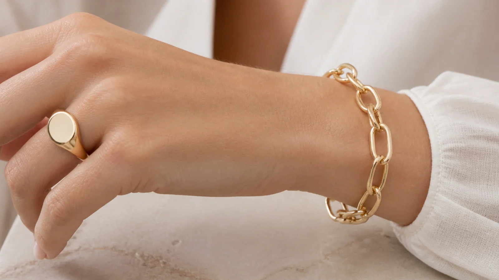 Faceless close-up of a solid gold signet ring and a substantial gold link bracelet with heirloom weight