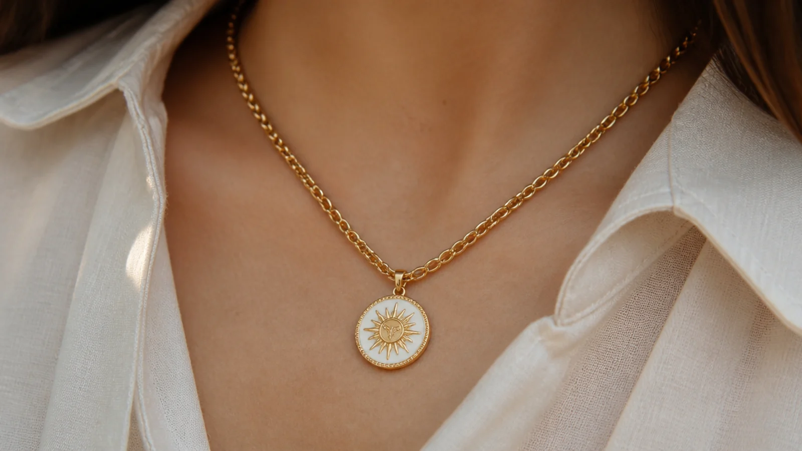 Faceless close-up of an enamel and gold medallion pendant on a heavy solid gold belcher chain