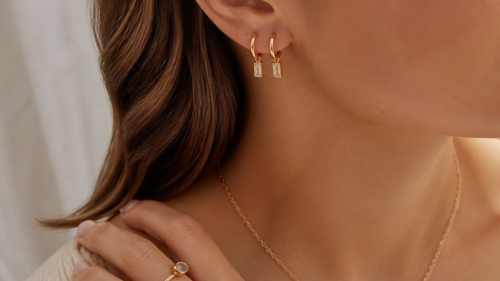 Faceless close-up of dainty nickel-free gold-filled earrings and a delicate chain for sensitive skin