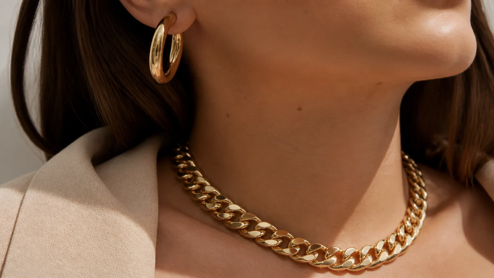 Faceless close-up of a heavy chunky solid gold curb chain and a thick gold hoop with real weight