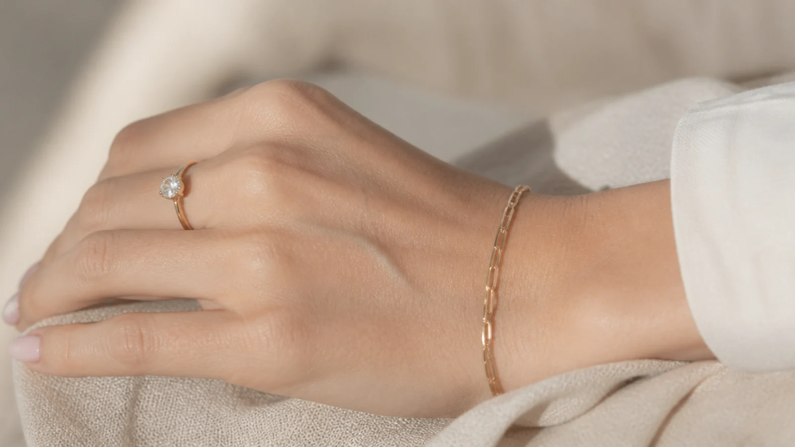 Faceless close-up of a classic solitaire diamond engagement ring and a fine gold link bracelet