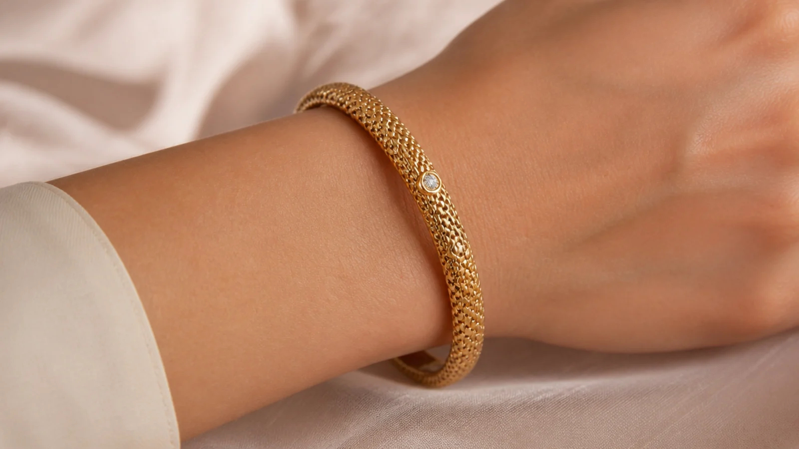 Faceless close-up of an intricately woven Italian gold bangle with a fine diamond accent