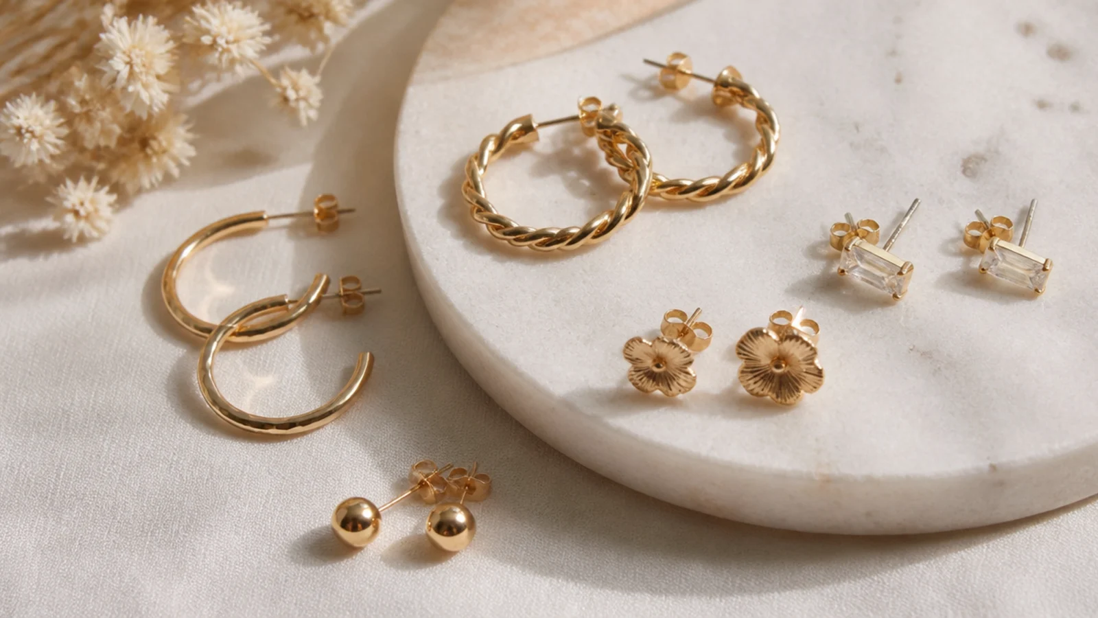 Faceless close-up of nickel-free gold-filled and titanium earrings arranged for sensitive-skin wearers