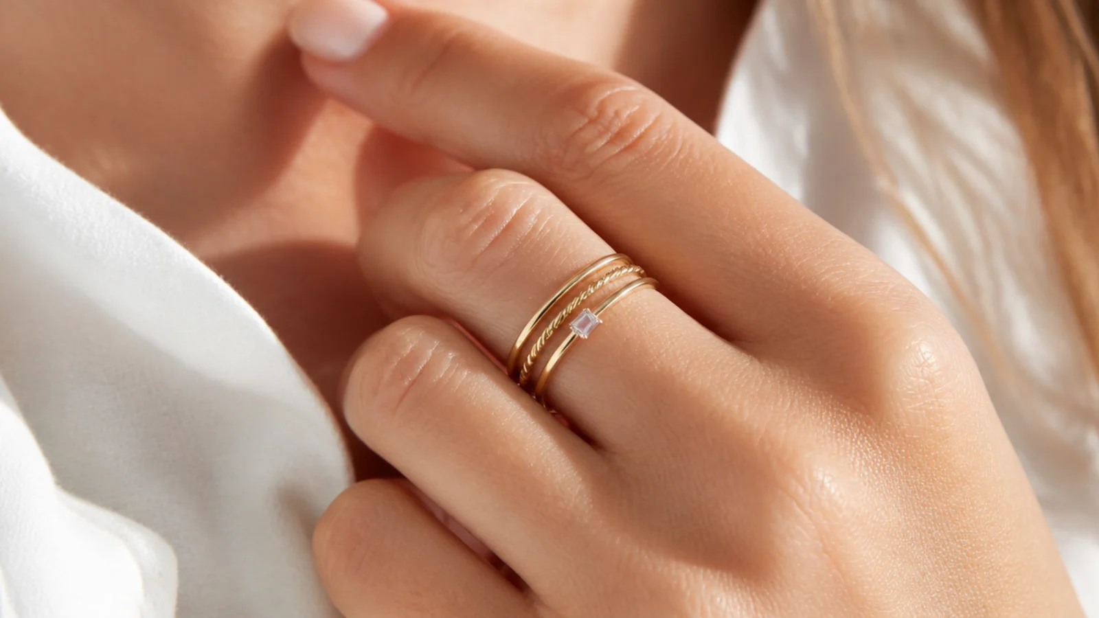Faceless close-up of three thin gold stacking rings worn together on one finger