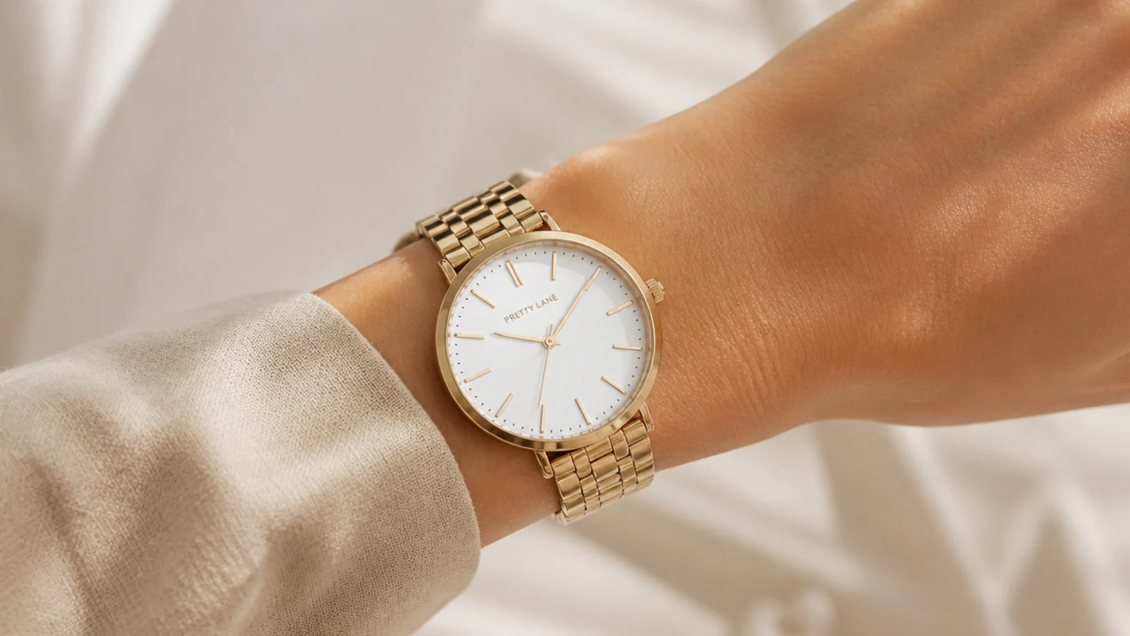 Faceless close-up of a slim gold everyday watch with a clean white dial on the wrist