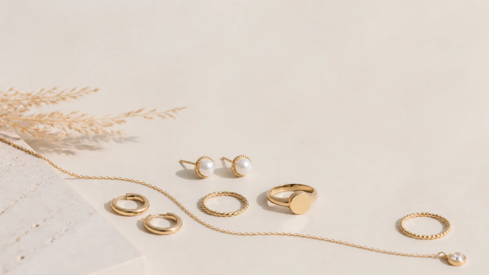 Faceless flat lay of classic everyday jewelry essentials in gold on a neutral background